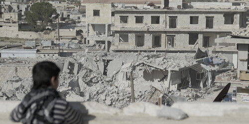 Ein Kind in Syrien blickt auf eine von Bomben zerstörte Stadt Ein Kind in Syrien blickt auf eine von Bomben zerstörte Stadt